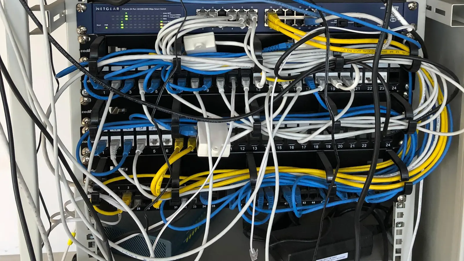 Interno di un armadio rack con switch e patch panel collegati da numerosi cavi di rete